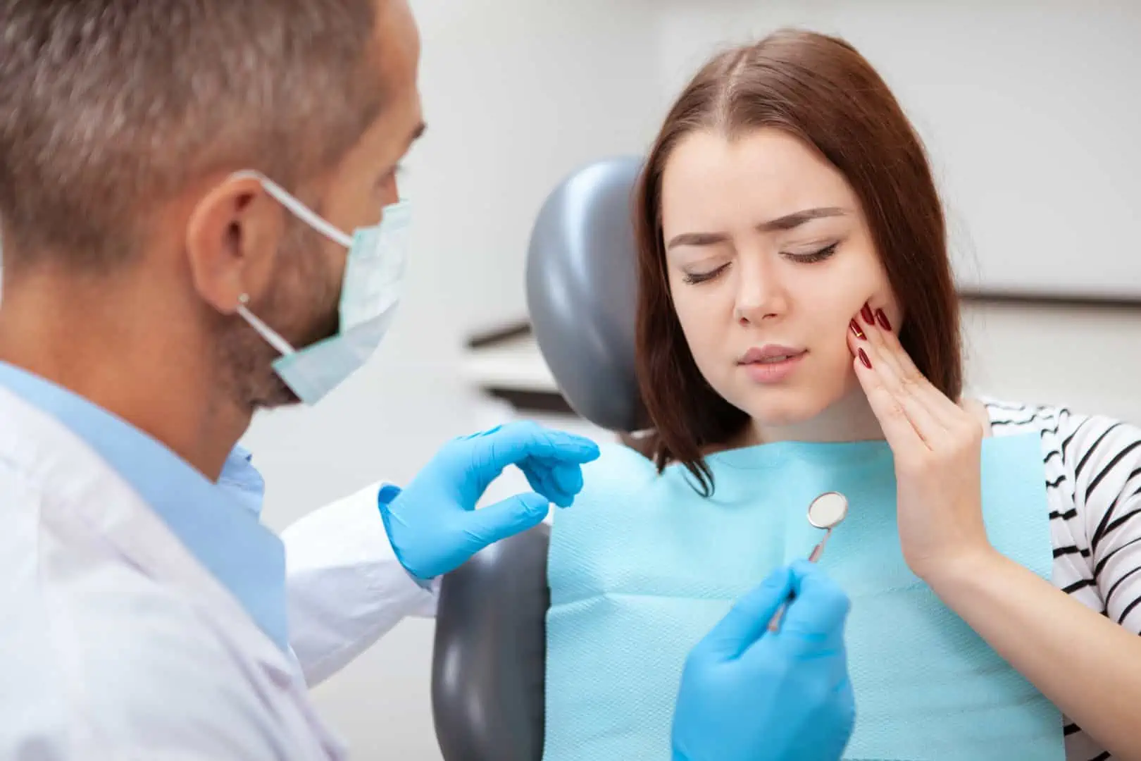 Patient holding her jaw in pain before an emergency dental visit